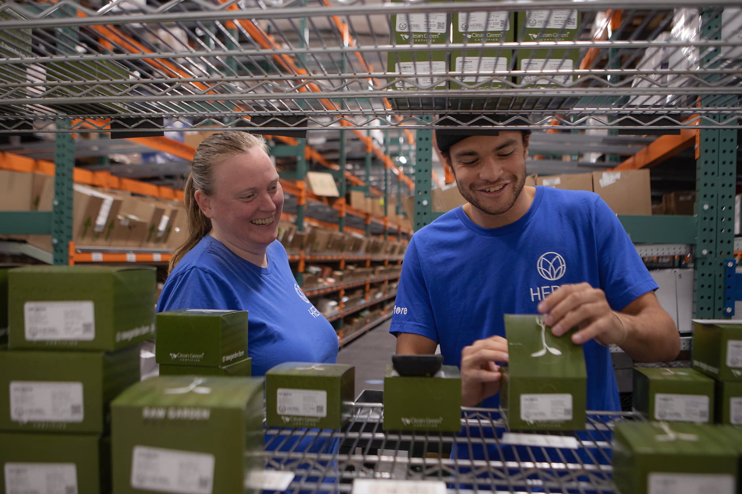 Two dispensary employees smiling while checking inventory shelves in the storeroom