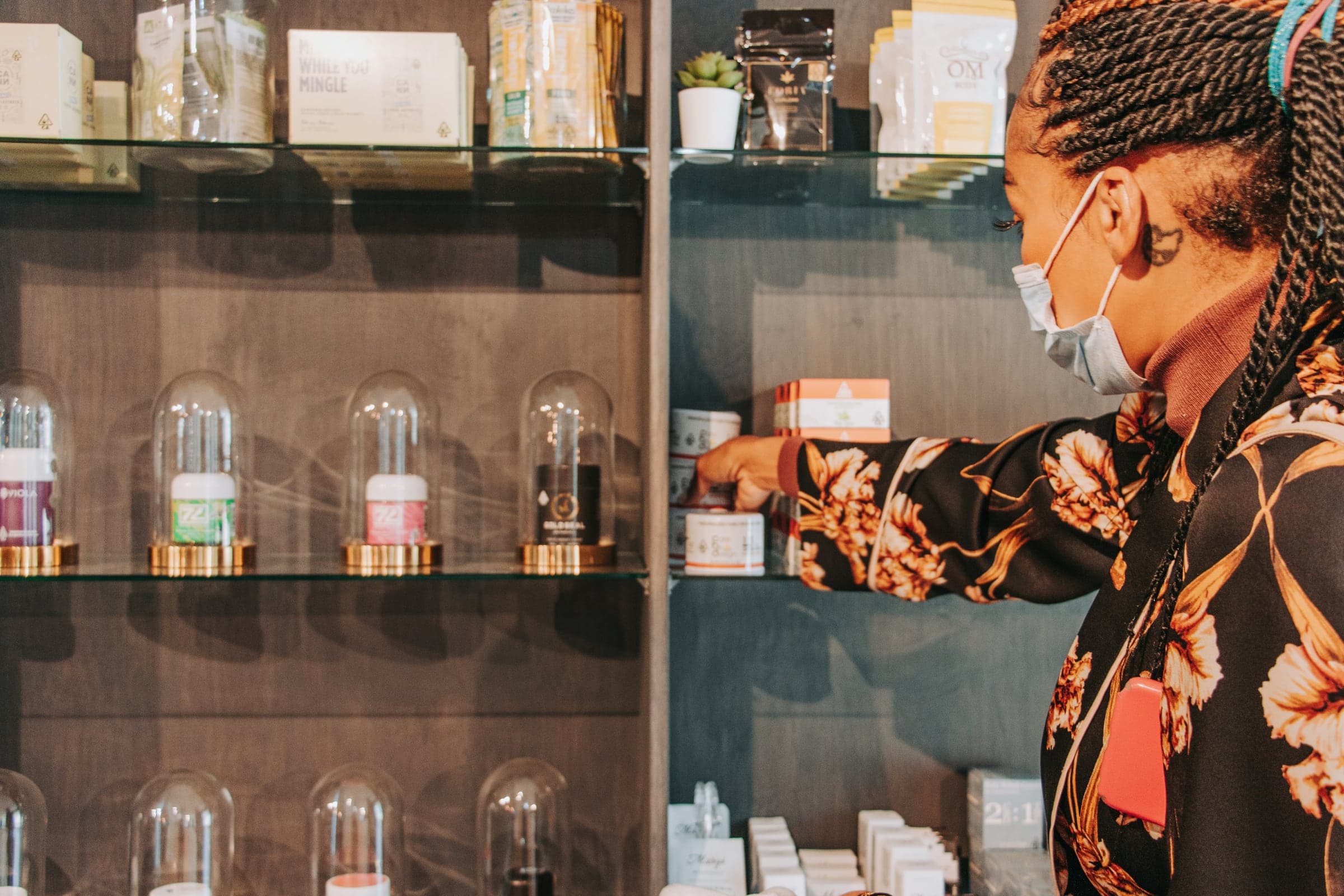 A woman with braided hair grabs some flower from a display shelf