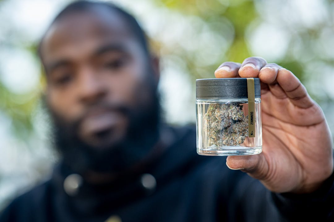 A social equity applicant holds a jar of cannabis flower