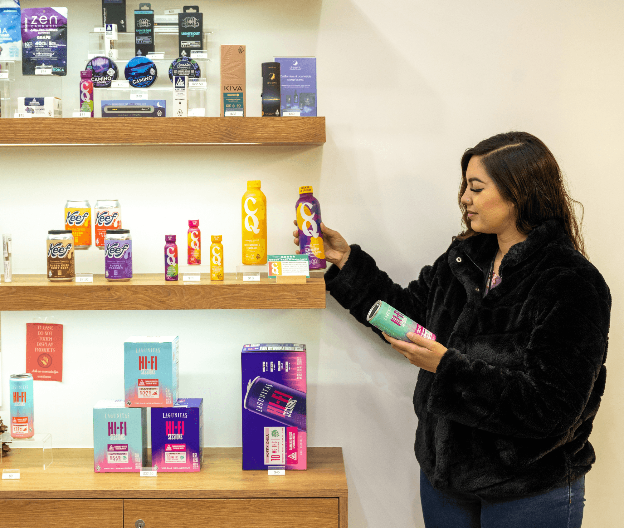 A customer browses a dispensary shelf stocked with neatly labeled cannabis beverages, confidently comparing products. The organized displays highlight transparent information, reinforcing the ease of staying compliant while shopping or managing inventory.
