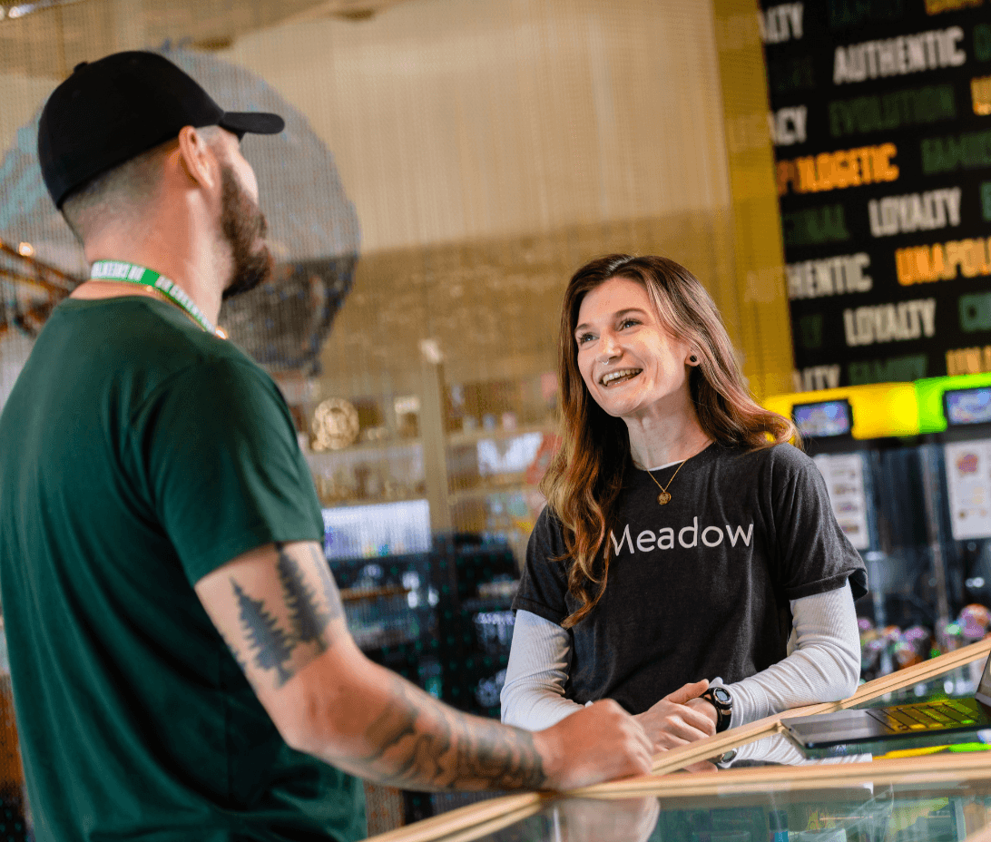 In the image, a Meadow representative is engaged in conversation with a dispensary manager inside Dr Greenthumb's dispensary.
The interaction exemplifies Meadow's commitment to exceptional client support. The representative is seen offering personalized assistance, reflecting Meadow's reputation for industry-leading support. Services such as white glove onboarding, comprehensive team training, Metrc and compliance guidance, troubleshooting, and business growth strategies are highlighted through this genuine, collaborative exchange.