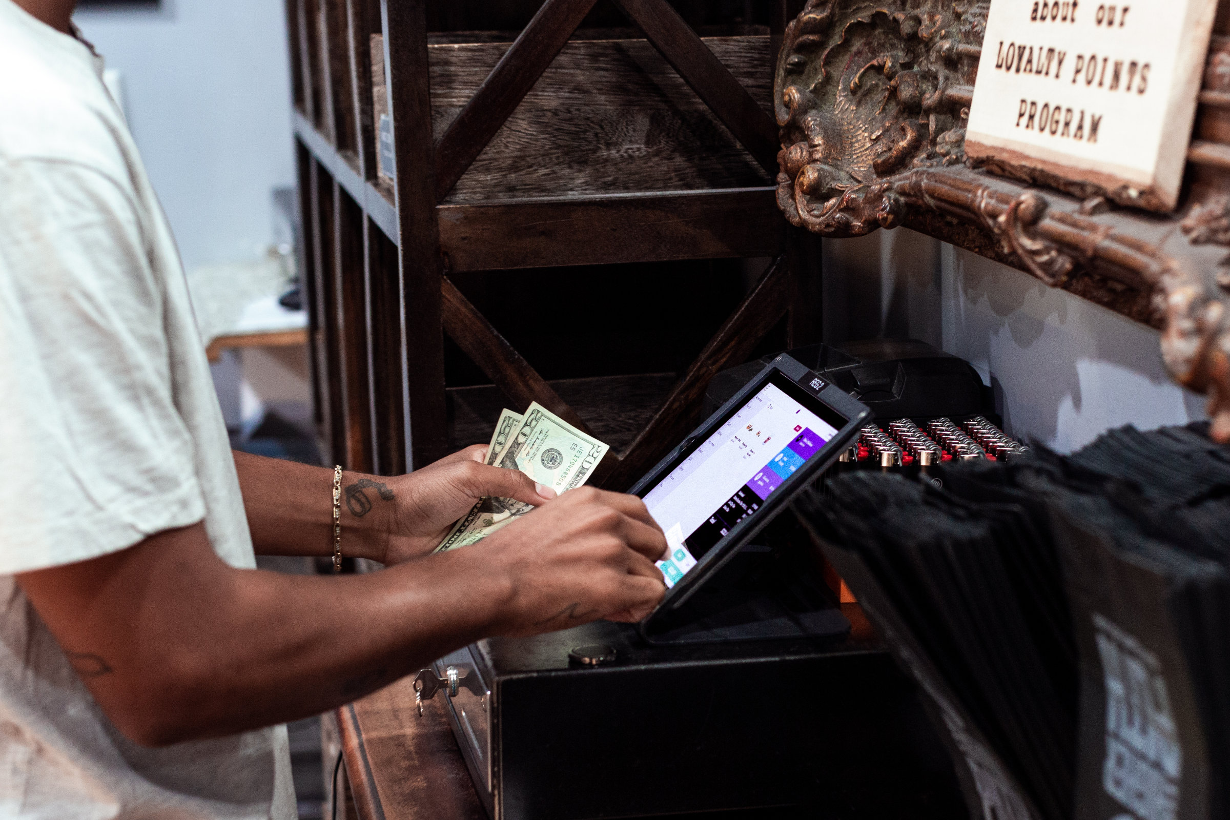Man handling cash at a Meadow POS iPad