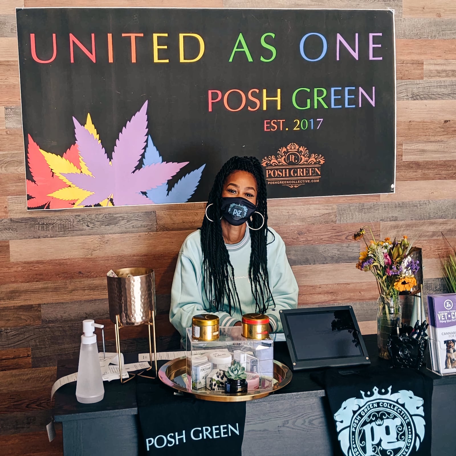 A woman under a sign saying 'United As One, Posh Green'